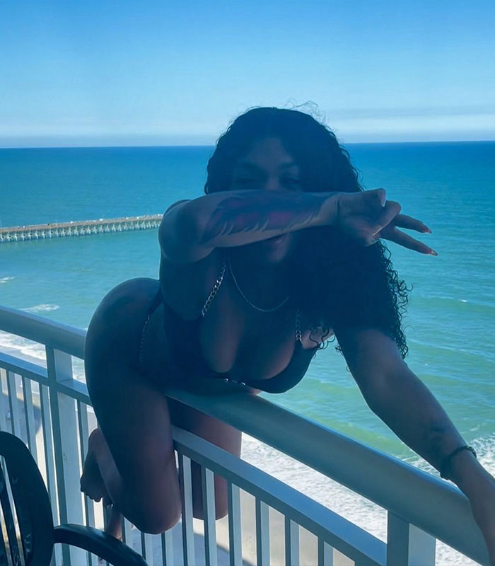 A woman poses on a balcony overlooking the ocean for a viral video that angered viewers