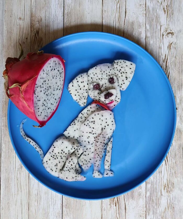 A cute Dalmatian dog made from sliced dragon fruit on a blue plate, a creative everyday food art piece