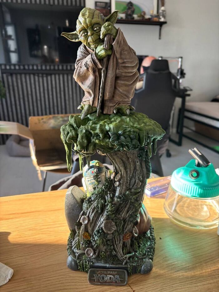 A detailed 3D print of Yoda standing on a mossy tree stump with R2-D2 carved inside.