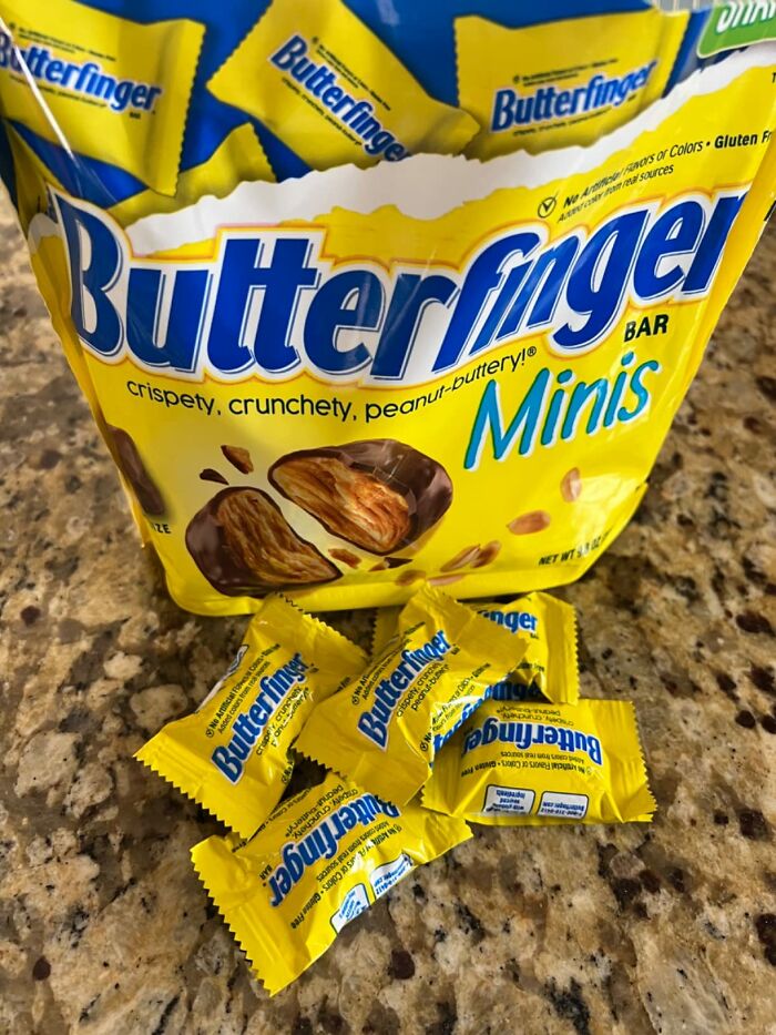 Bag of Butterfinger Minis with individual wrapped chocolates scattered on a counter for Best Halloween Candies.