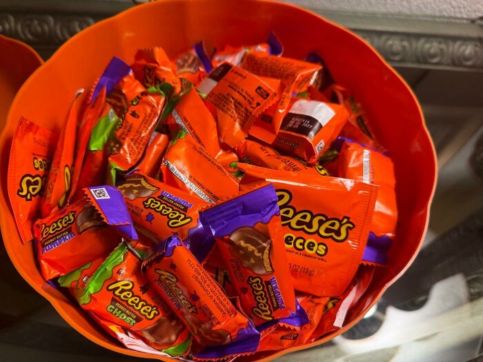An orange bowl filled with individually wrapped Reese's Peanut Butter Cups, top choice for Best Halloween Candies.