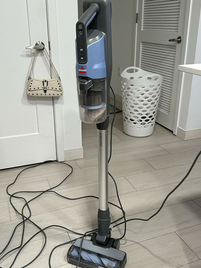 A Bissell stick vacuum standing on a wooden floor, popular on Big Deal Days.