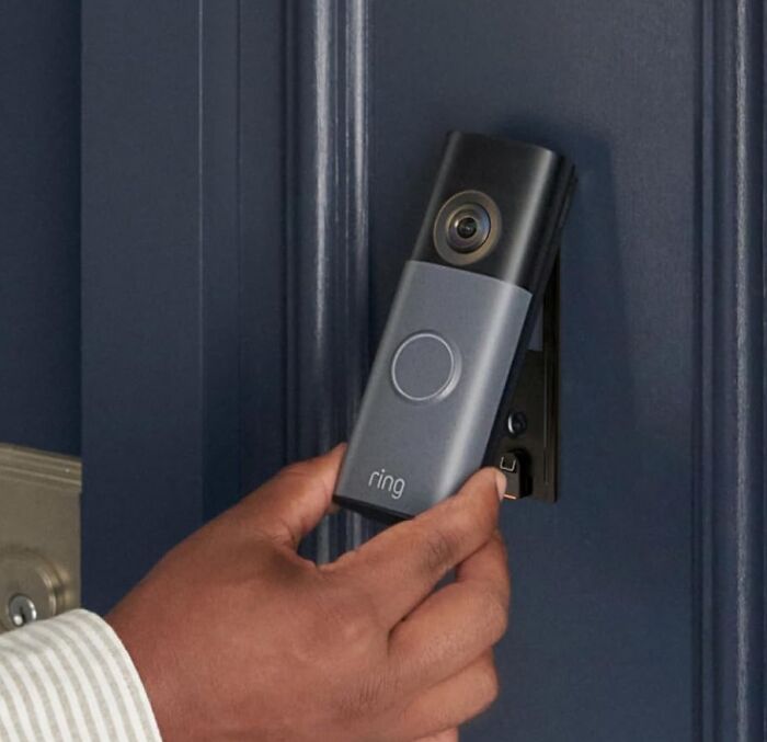 A hand mounting a Ring video doorbell on a dark door, a featured Amazon Big Deal Days trending item