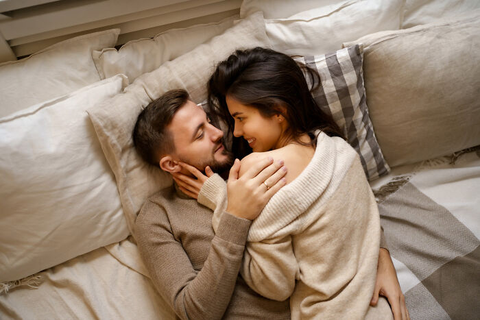 A loving couple lying together on a bed, reflecting back on past divorce stories.