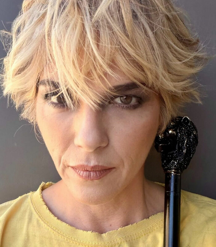 A close-up portrait of Selma Blair holding a walking cane with an ornate handle. A close-up portrait of Selma Blair holding a walking cane with an ornate handle.