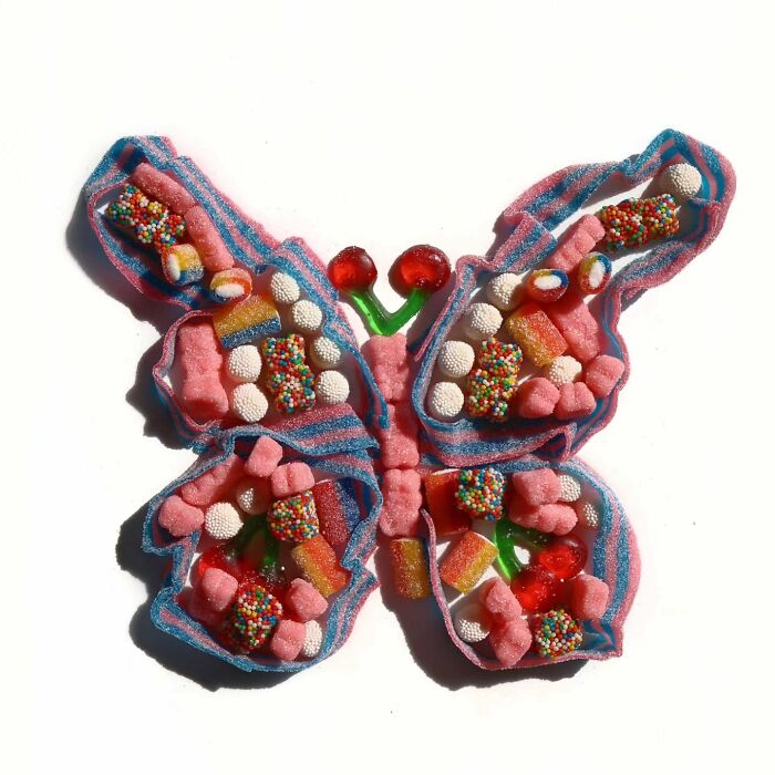 Playful food art of a butterfly made from pink and blue sour gummy candies and sprinkles by Sarah Rosado.