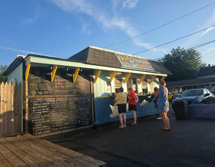 Customers lining up outside the viral ice cream shop with menu boards. Customers lining up outside the viral ice cream shop with menu boards.