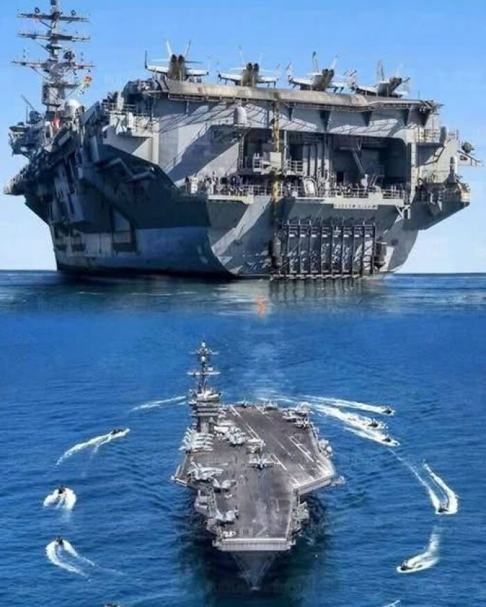 Cool perspective showing a massive aircraft carrier next to smaller escort boats in the ocean