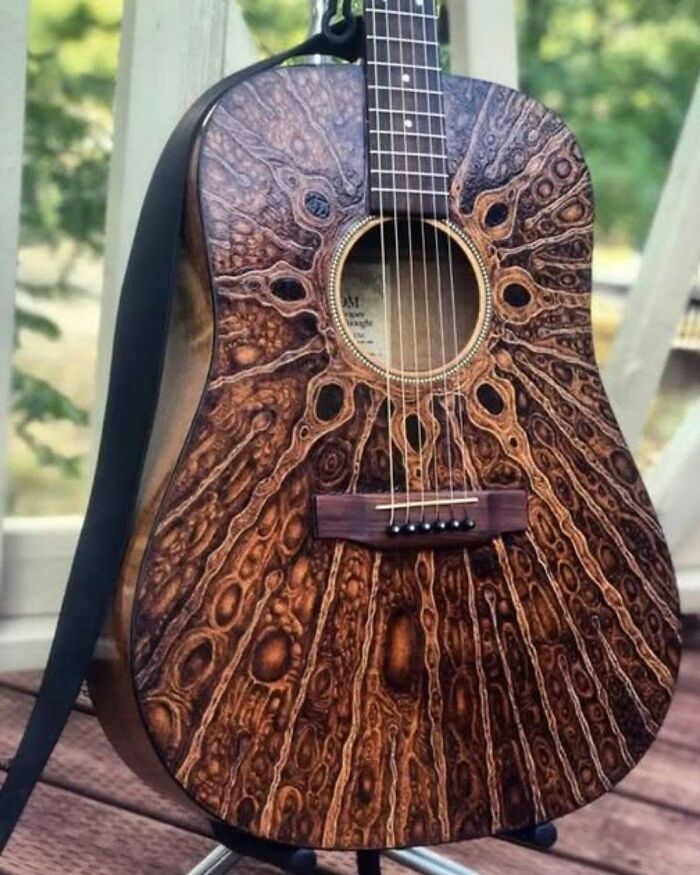 An acoustic guitar with an interesting wood grain pattern that looks like a human eye.
