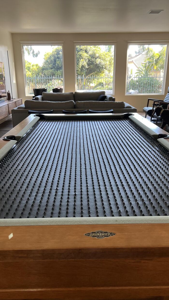 Pool table covered with a custom protective spiked cover made of 3D prints.