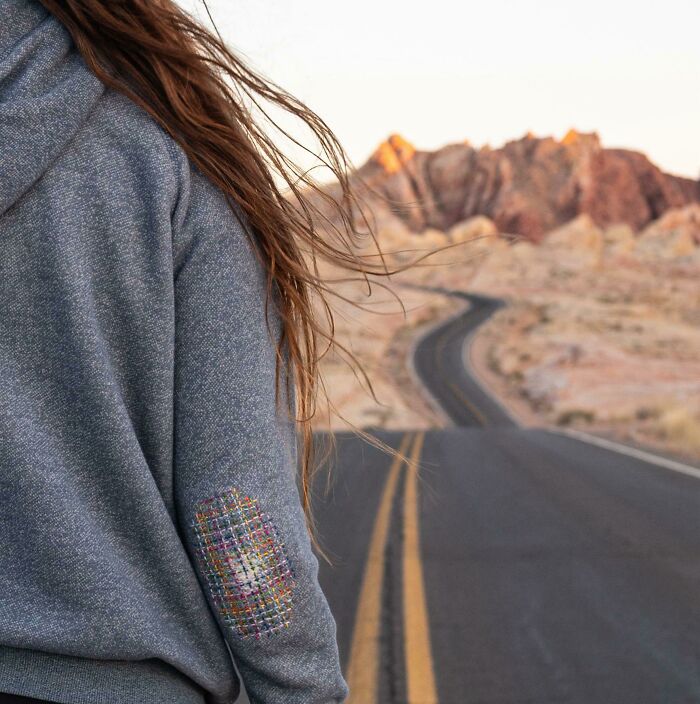 Person displaying a mended hoodie sleeve with a little creativity to save money on clothing repairs