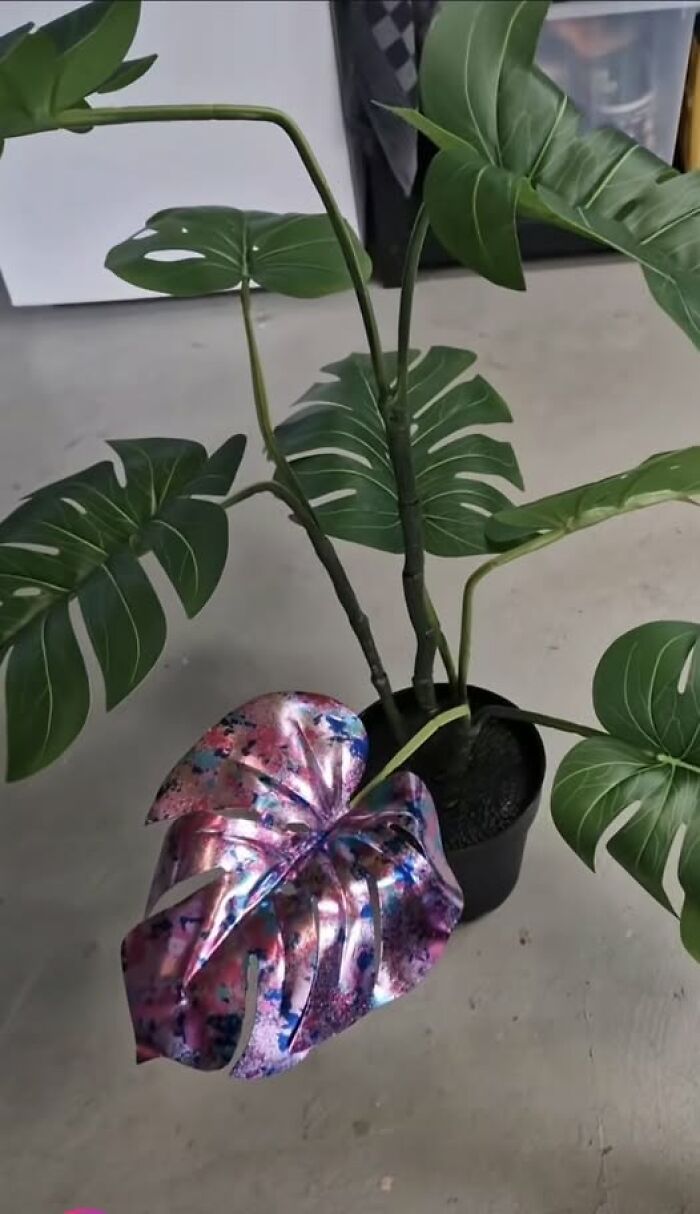 An artificial houseplant with one single leaf painted in metallic pink and blue, showcasing hilarious art projects.