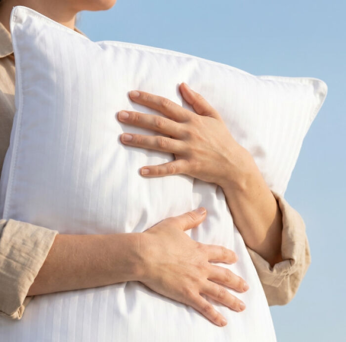 A person hugging a soft white sleeping pillow, one of the top Amazon Big Deal Days trending items