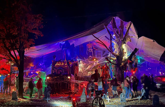 Crowded Halloween neighborhood display with decorations and visitors at night Crowded Halloween neighborhood display with decorations and visitors at night