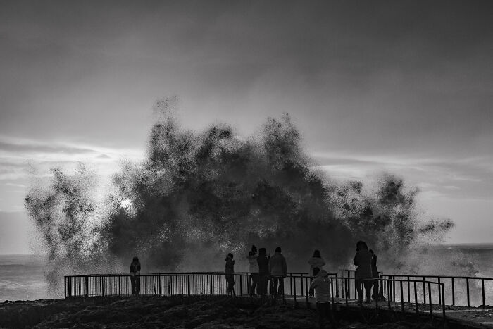 People standing on a viewing platform watching huge waves on a black sand beach in Iceland