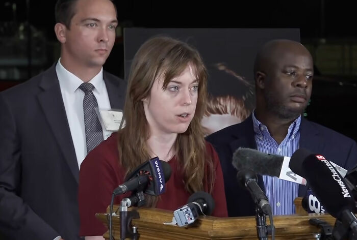 A woman speaking at a press conference with microphones, referencing Christa Pike memories