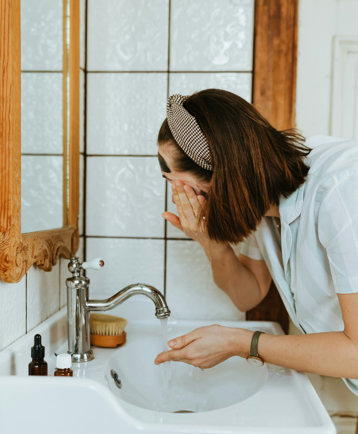 Woman washing her face in the sink to clean black spots on your nose. Woman washing her face in the sink to clean black spots on your nose.