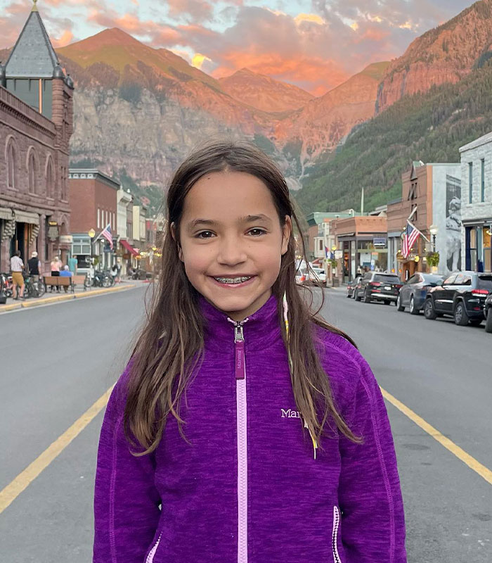 Girl standing on street with mountains at sunset in background