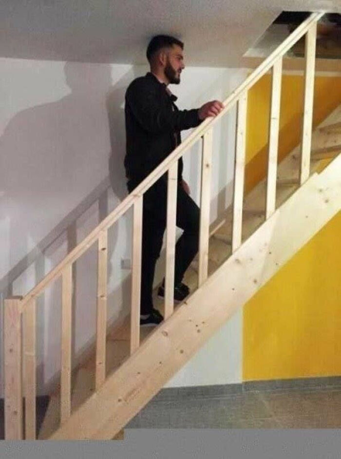 A man standing on stairs with no headroom, illustrating a home renovation design fail.