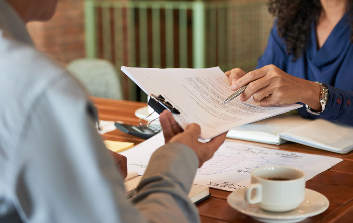 Two people reviewing legal paperwork on a table, illustrating legal battles in divorce stories.