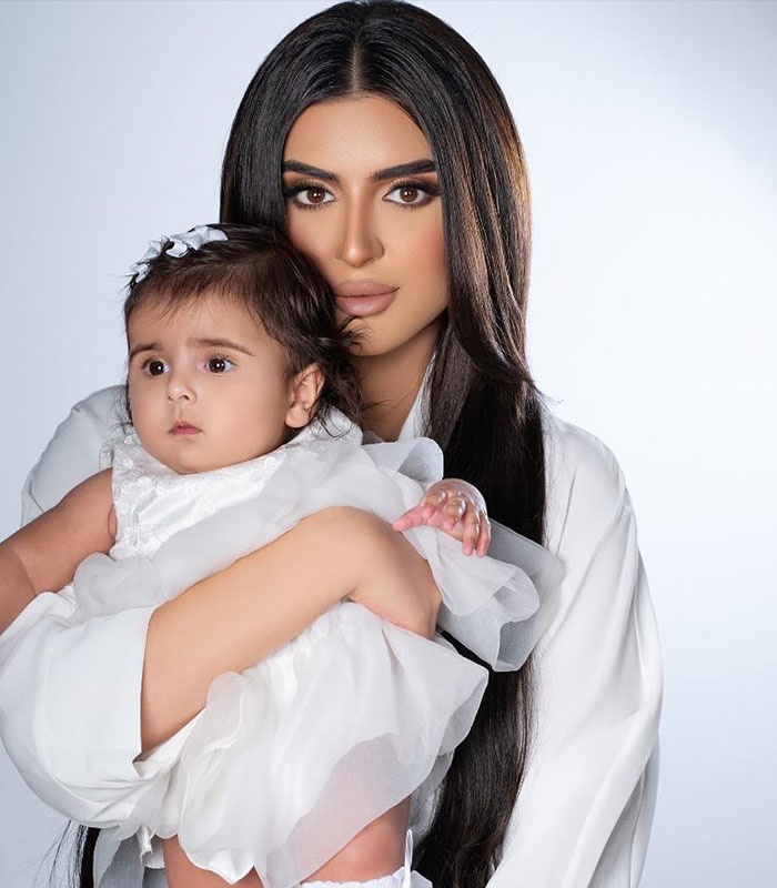 Royal mother holding child dressed in white in portrait photo