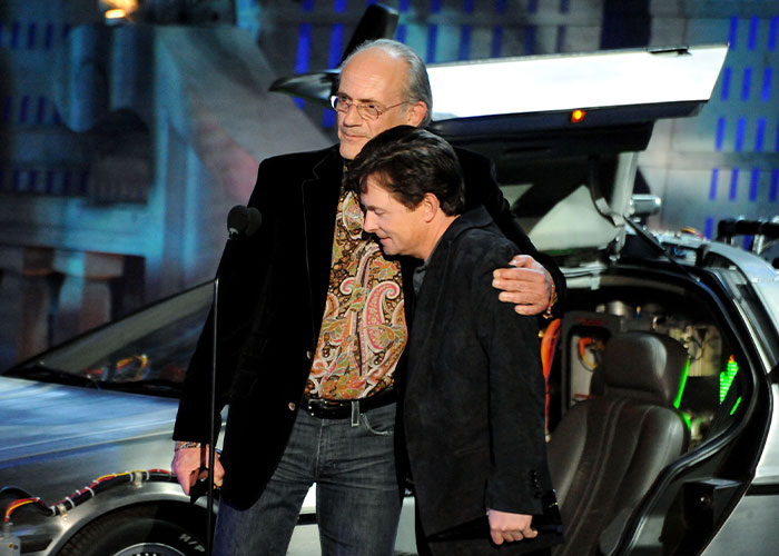 Christopher Lloyd hugging Michael J. Fox on stage in front of the DeLorean time machine Christopher Lloyd hugging Michael J. Fox on stage in front of the DeLorean time machine