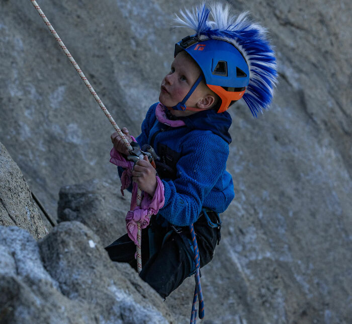 Young boy with a blue helmet climbing Yosemite's El Capitan rock face