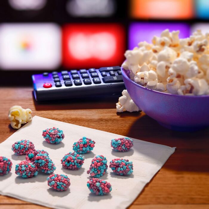 A cluster of blue and pink Nerds Clusters candies on a paper napkin near popcorn, great for Best Halloween Candies.