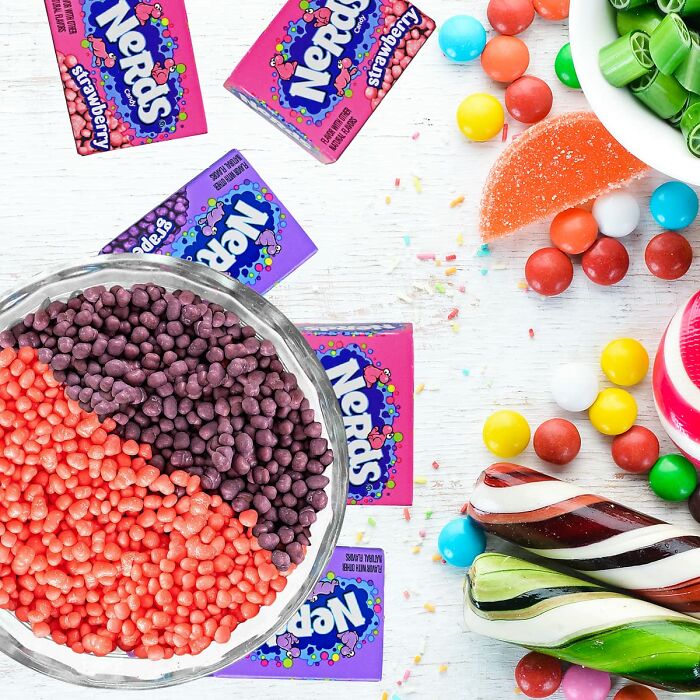 Colorful Nerds candy scattered near a glass bowl filled with red and purple Nerds for Best Halloween Candies.