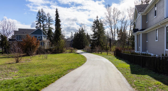 A paved neighborhood path surrounded by trees and houses, representing suburban safety and emergency tips.