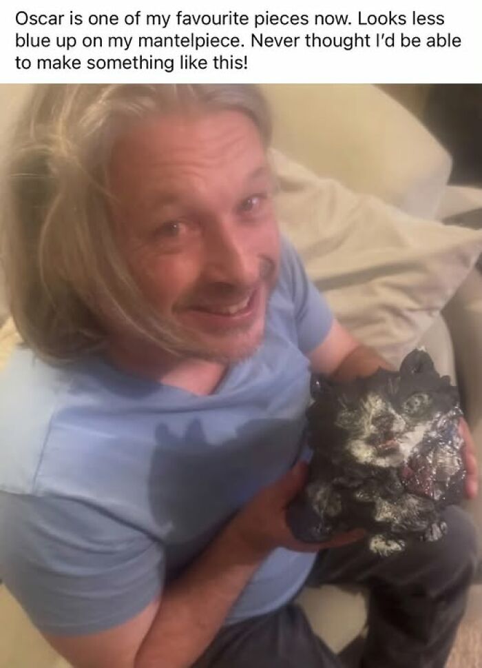 A man smiling and holding up a poorly made clay cat, representing hilarious crafts and art projects.