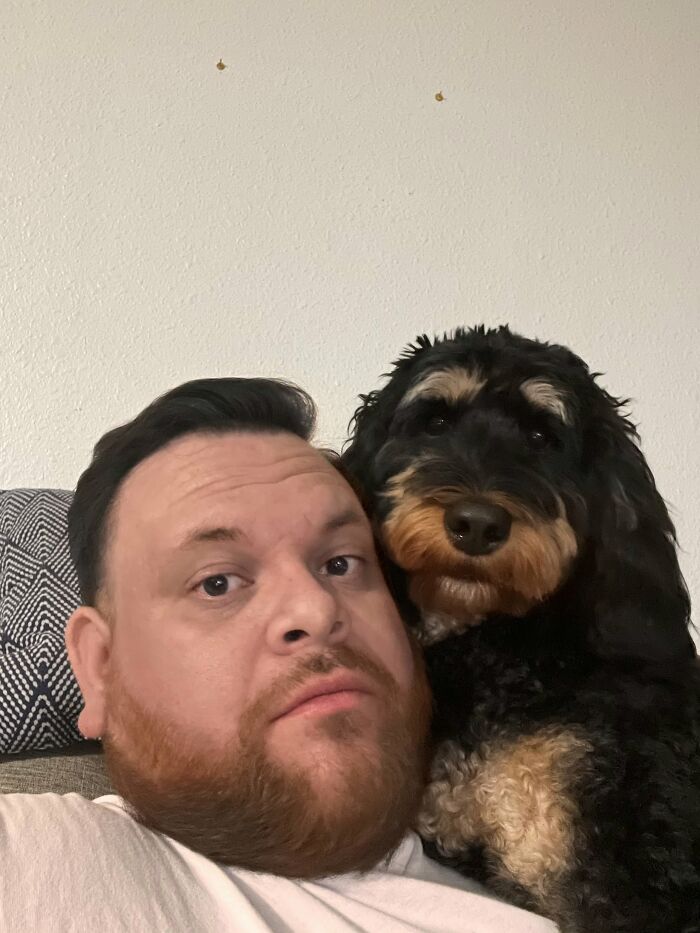 A man with a red beard next to his dog that looked like its owner with a similar black and tan pattern