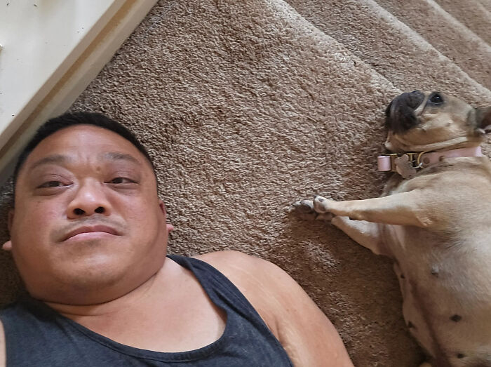 A man lying on the floor next to his look-alike pet dog