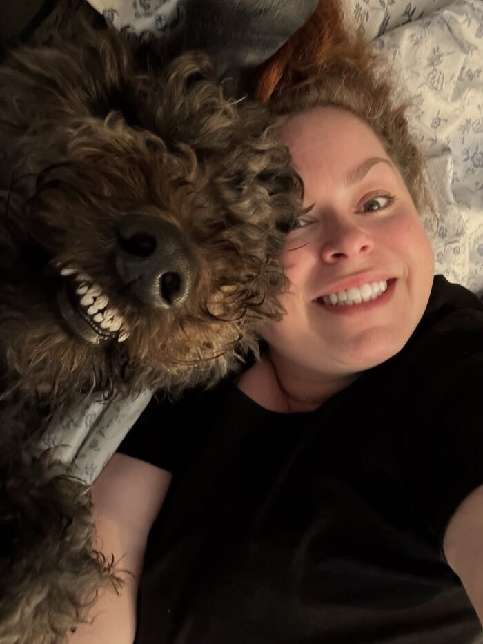 A woman and her fluffy dog showing matching wide-toothed smiles, showing pets look like owners