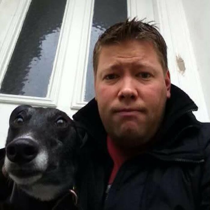 A man and his black greyhound making similar serious expressions, proving pets look like owners