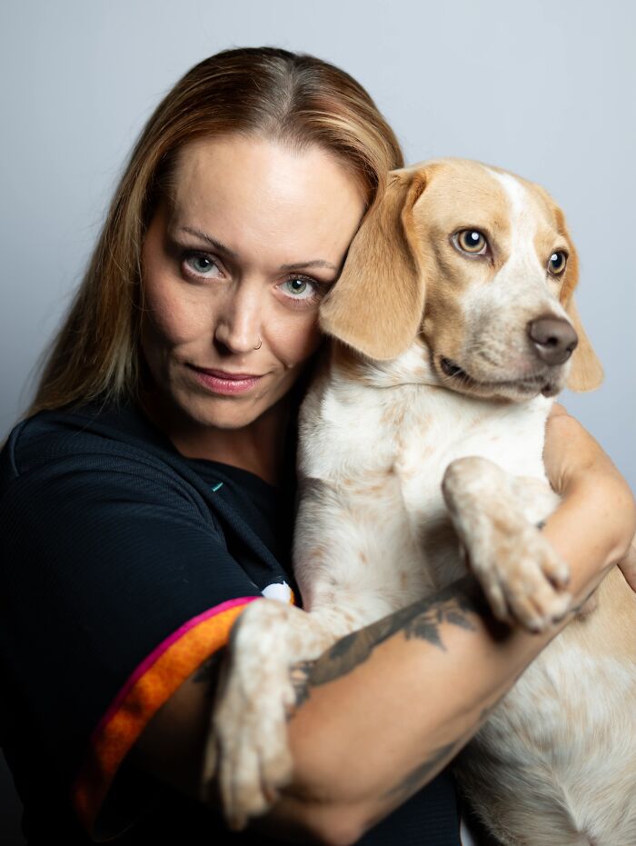 A woman with light brown hair holding her matching beagle dog, showing pets that look like their owners