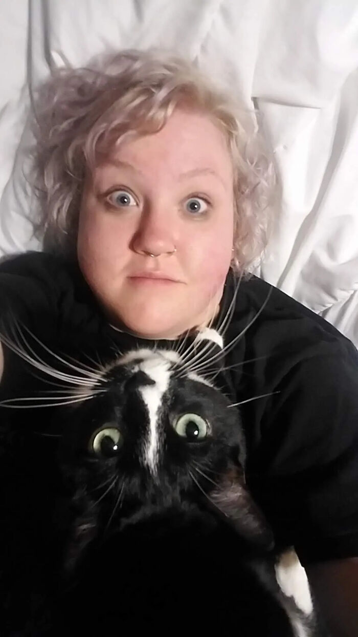 A wide-eyed blonde woman and her black and white cat, showing how pets look like owners