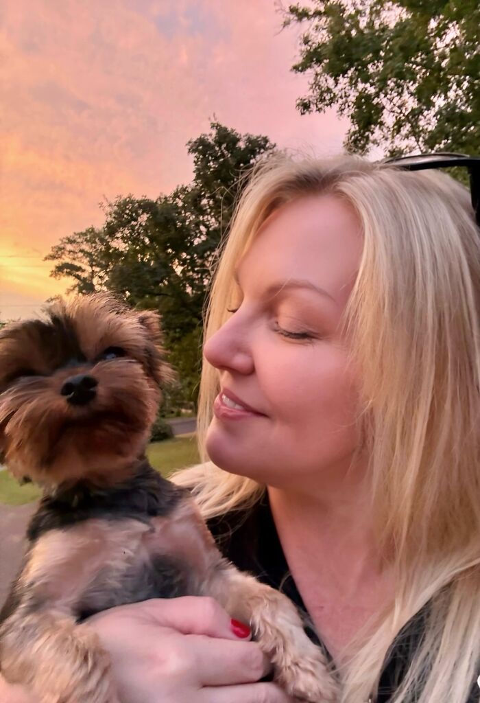 A smiling blonde woman holding her Yorkie dog, illustrating pets look like owners
