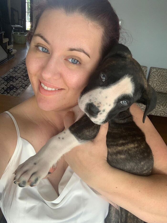 Woman with blue eyes hugging her puppy with matching blue eyes, demonstrating how pets look like their owners.