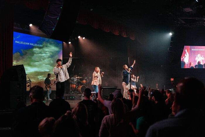 Performers singing on stage before a crowd, exemplifying modern cults worshipping.