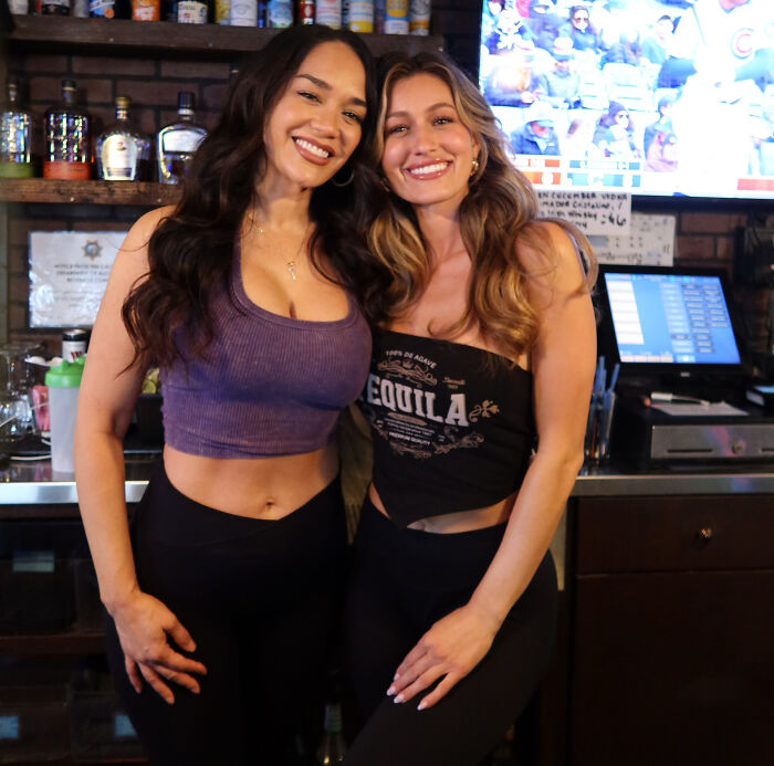 Two smiling bartenders standing together behind the counter of a California bar.
