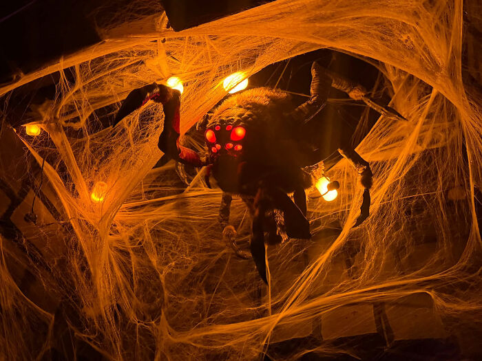 Giant spider with glowing red eyes in Halloween display covered in spider webs Giant spider with glowing red eyes in Halloween display covered in spider webs