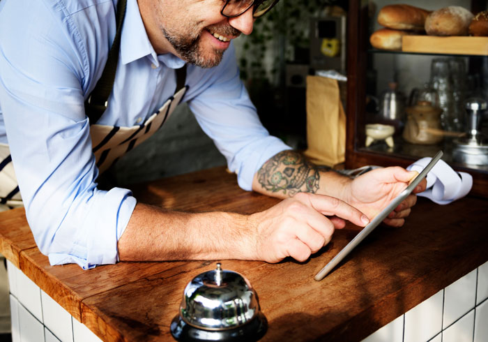 A happy waiter using a digital tablet at a cafe counter. A happy waiter using a digital tablet at a cafe counter.