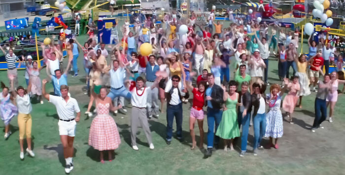 Large crowd dancing scene from Grease, illustrating context for How Do Men Lack Self-Awareness.