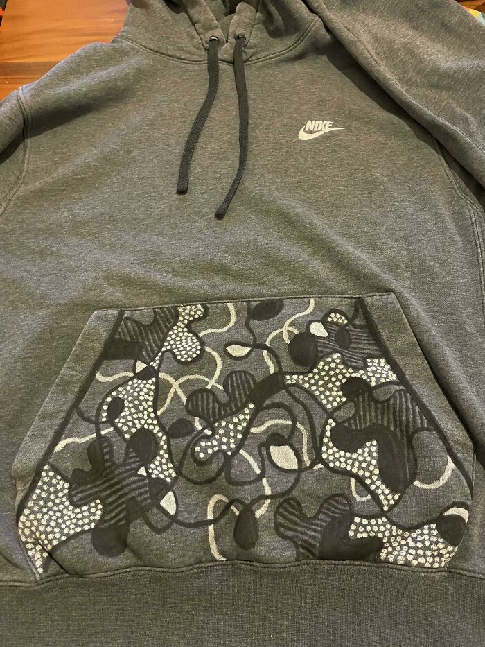 Grey Nike hoodie with custom camo pattern hand drawn on front pocket showing creativity to save money.