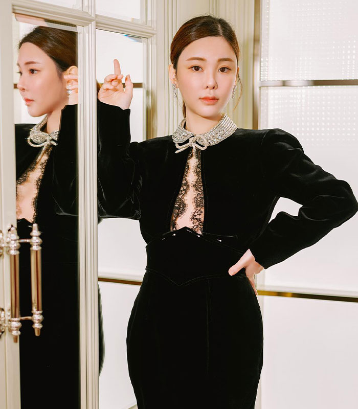 Woman in black dress posing by mirror showing confident look Woman in black dress posing by mirror showing confident look