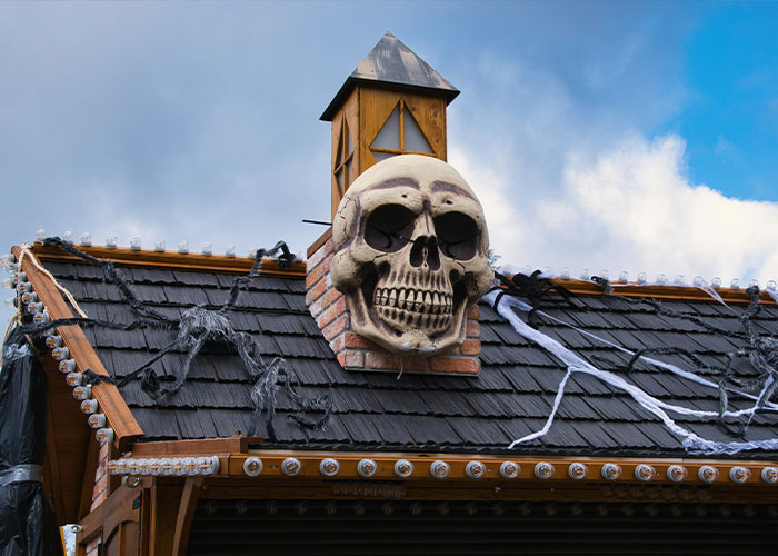 A large skull Halloween decoration installed on the roof of a house.