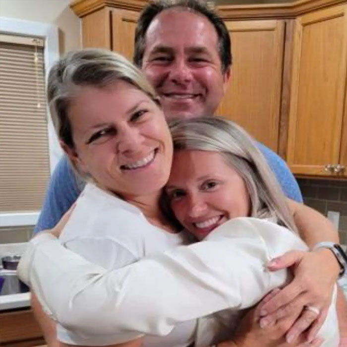 Three people hugging, representing family support for the female employee involved in the Amazon exec case