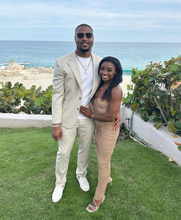 Simone Biles and husband Jonathan Owens posing together near the beach dressed in stylish formal wear