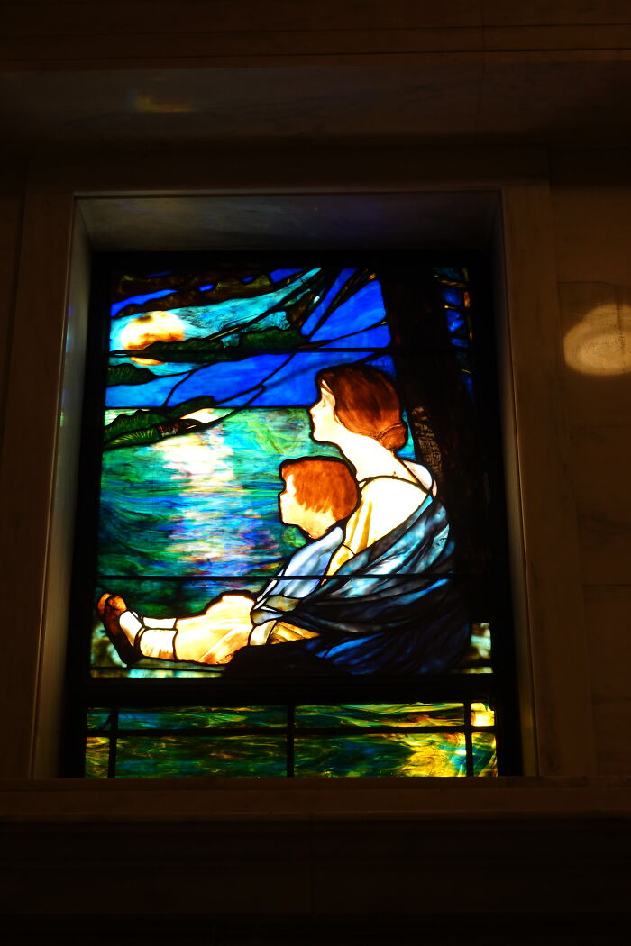 Stained glass window of a woman and child sitting by a lake at sunset Stained glass window of a woman and child sitting by a lake at sunset